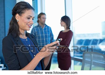 Stock Photography - Businesswoman using cell phone in office. Fotosearch