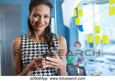 Businesswoman using cell phone in office View Large Photo Image Stock Photography - Businesswoman using cell phone in office. Fotosearch