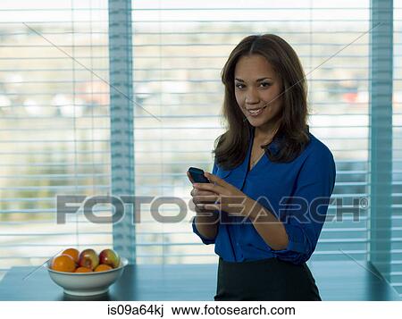Stock Image - Businesswoman using cell phone. Fotosearch