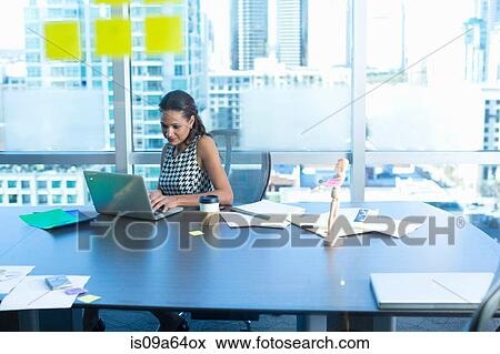 Stock Photo - Businesswoman using laptop at desk. Fotosearch