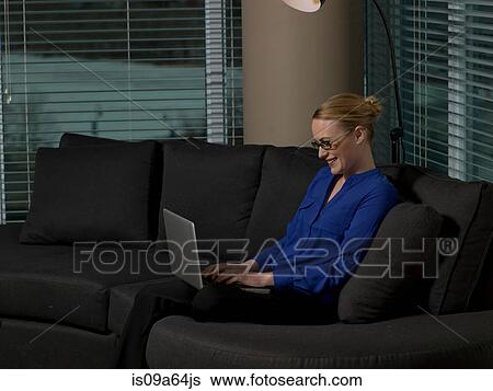 Stock Photograph - Businesswoman using laptop on sofa. Fotosearch