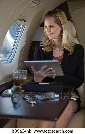 Stock Image - Businesswoman using tablet on airplane. Fotosearch