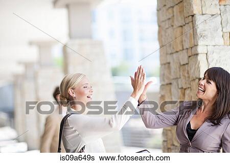 Businesswomen high giving in walkway View Large Photo Image Stock Photograph - Businesswomen high giving in walkway. Fotosearch