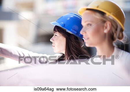 Stock Image - Businesswomen reading blueprints. Fotosearch