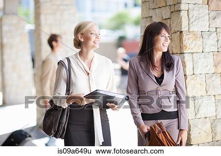 Stock Photograph - Businesswomen standing in walkway. Fotosearch