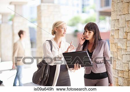 Stock Image - Businesswomen talking in walkway. Fotosearch