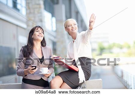 Stock Photo - Businesswomen talking on balcony. Fotosearch