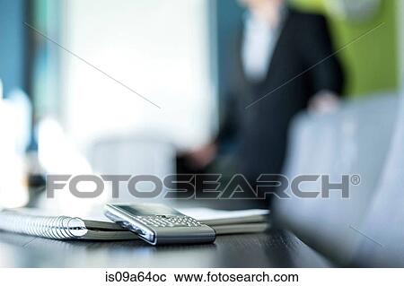 Stock Image - Cell phone and notebook on desk. Fotosearch