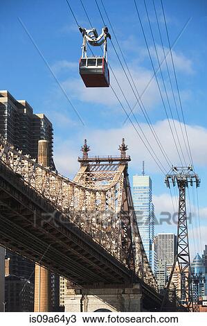 Stock Image - Chairlift over urban bridge. Fotosearch