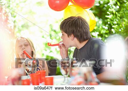 Stock Image - Children blowing noisemakers at party. Fotosearch