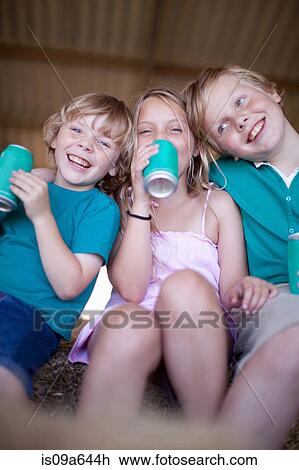 Stock Image - Children drinking soda in garage. Fotosearch
