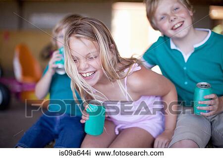 Stock Image - Children drinking soda in garage. Fotosearch