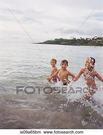 Picture - Children playing in waves on beach. Fotosearch