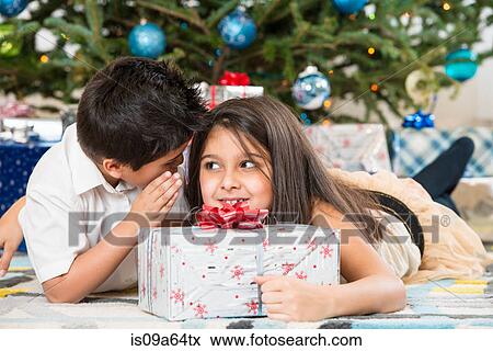 Stock Photo - Children whispering by Christmas tree. Fotosearch