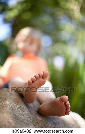 Stock Image - Close up of boy's feet on rock. Fotosearch