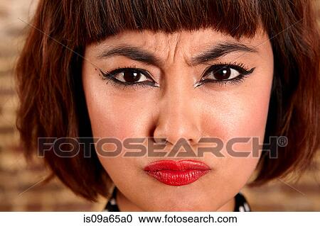 Stock Image - Close up of woman's frowning face. Fotosearch