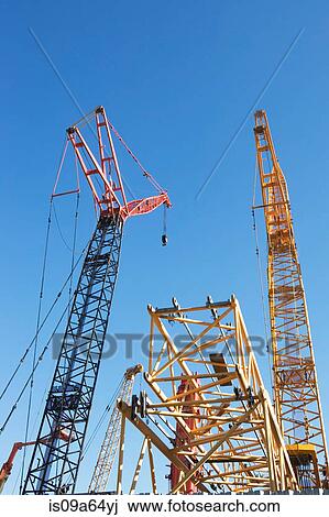 Stock Image - Colorful cranes against blue sky. Fotosearch