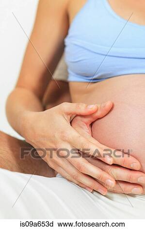 Stock Image - Couple holding woman's pregnant belly. Fotosearch