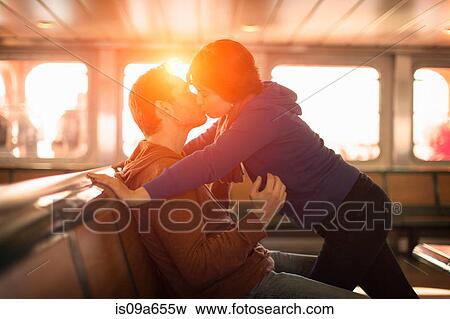 Stock Photo - Couple kissing on ferry at sunset. Fotosearch