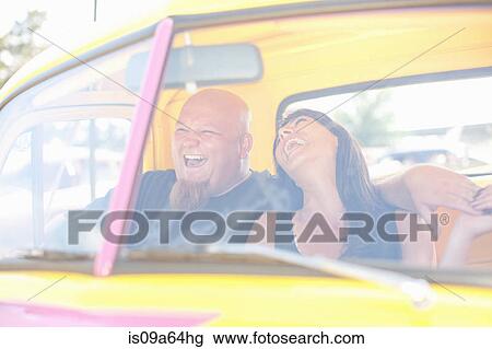 Stock Image - Couple laughing in colorful car. Fotosearch
