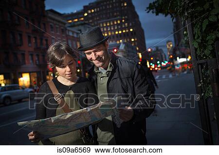 Stock Photo - Couple reading city map at night. Fotosearch