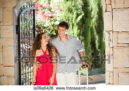 Stock Photo - Couple rolling luggage in hotel. Fotosearch