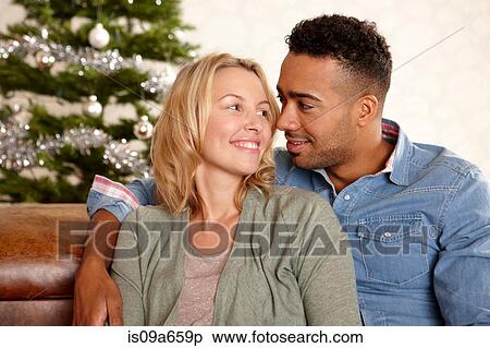 Stock Photography - Couple smiling together on sofa. Fotosearch