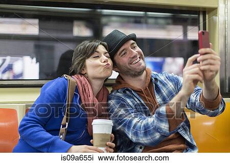 Stock Image - Couple taking picture on subway. Fotosearch