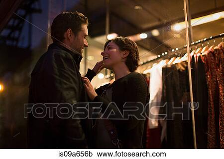Stock Image - Couple talking on city street at night. Fotosearch