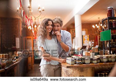 Stock Image - Couple tasting olives in grocery. Fotosearch