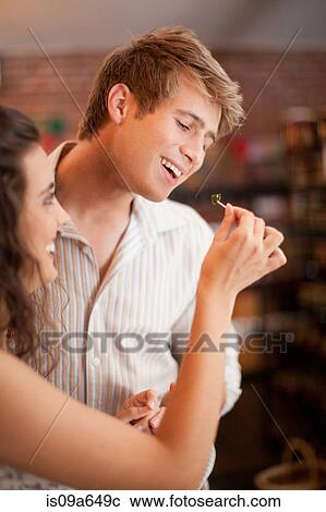 Stock Image - Couple tasting olives in grocery. Fotosearch