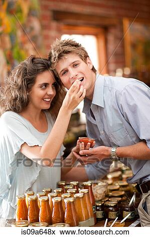 Stock Photo - Couple tasting preserves in grocery. Fotosearch
