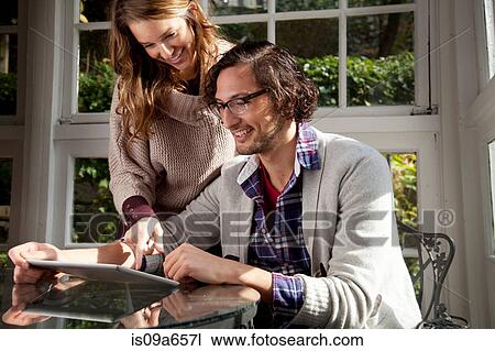 Couple using tablet computer at table View Large Photo Image Stock Image - Couple using tablet computer at table. Fotosearch