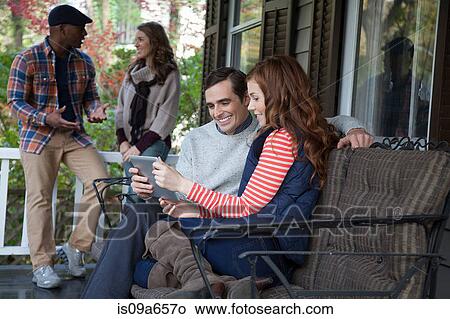 Picture - Couple using tablet computer on porch. Fotosearch
