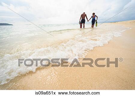 Stock Photo - Couple walking on tropical beach. Fotosearch