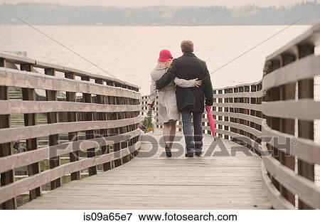 Couple walking on wooden dock View Large Photo Image Stock Photo - Couple walking on wooden dock. Fotosearch