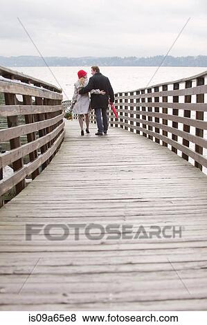 Couple walking on wooden dock View Large Photo Image Stock Photo - Couple walking on wooden dock. Fotosearch