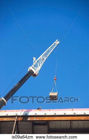 Picture - Crane loading equipment on building. Fotosearch