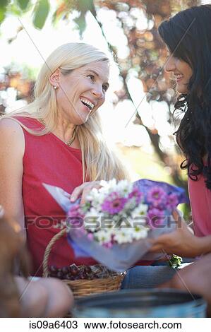 Stock Image - Daughter giving mother flowers. Fotosearch
