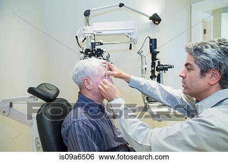Stock Photograph - Doctor giving patient eye exam. Fotosearch