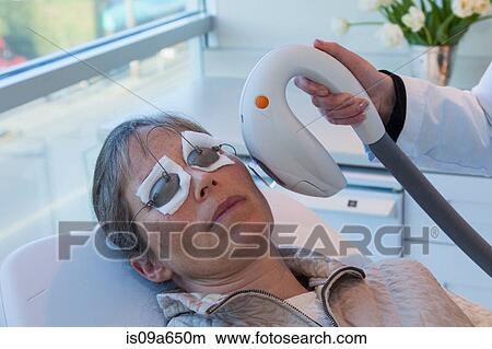 Picture - Doctor giving patient sunspot treatment. Fotosearch
