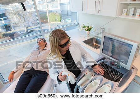 Stock Image - Doctor giving patient sunspot treatment. Fotosearch