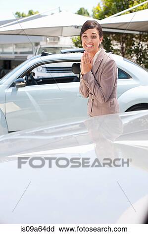 Stock Image - Excited woman cheering at car dealership. Fotosearch