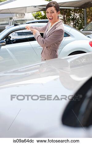 Stock Image - Excited woman pointing to new car. Fotosearch