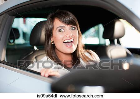 Stock Image - Excited woman sitting in car. Fotosearch
