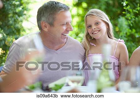 Stock Image - Father and daughter smiling at table. Fotosearch