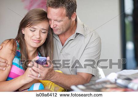 Stock Image - Father and daughter using cell phone. Fotosearch