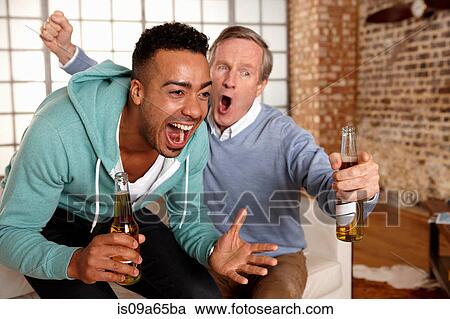 Stock Image - Father and son watching sports together. Fotosearch
