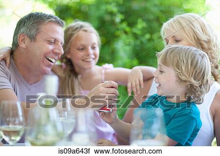 Stock Image - Father giving son soda at table. Fotosearch