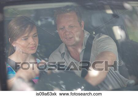 Stock Image - Father teaching teenage daughter driving. Fotosearch
